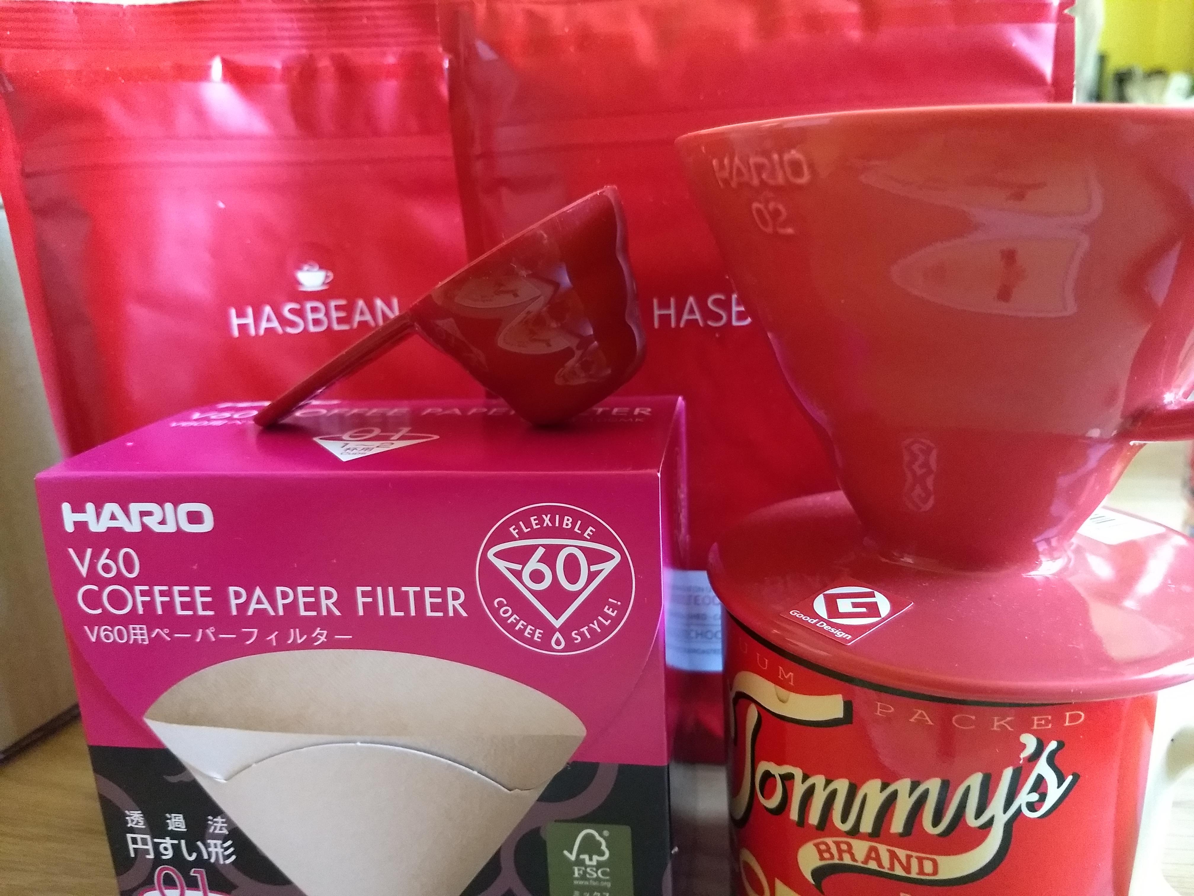 A Hario V60 coffee dripper next to some bags of coffe