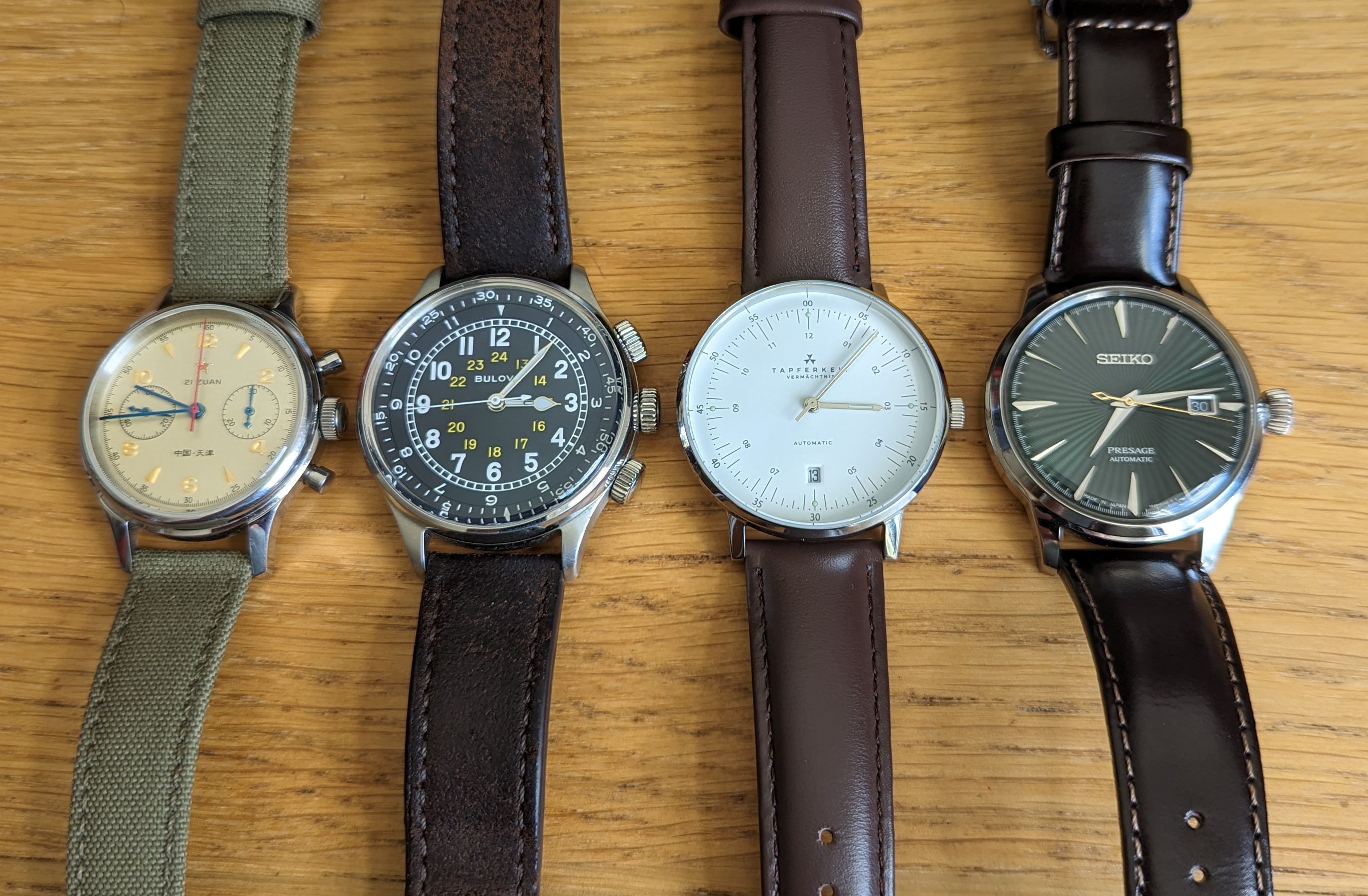 My collection of 4 mechanical watches lying face-up on my desk